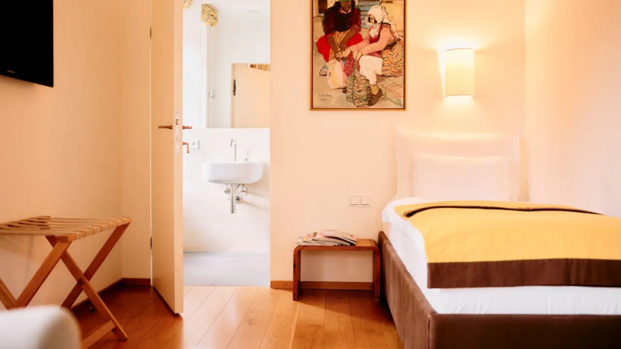 Komfortables Hotelzimmer mit Einzelbett, Holzboden und Zugang zum Badezimmer im G’Schlössl Murtal.