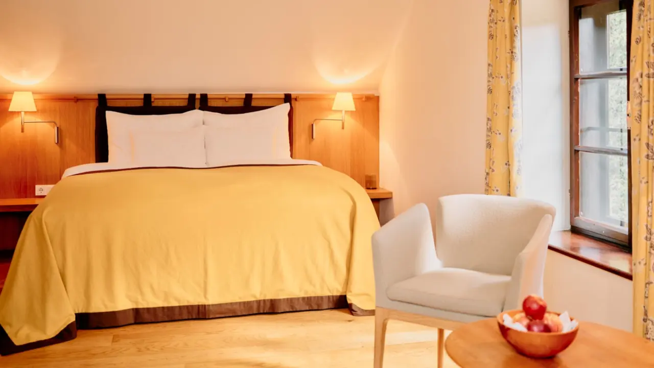 Gemütliches Doppelzimmer im G’Schlössl Murtal mit bequemen Bett, Leselampen und Sitzbereich am Fenster.