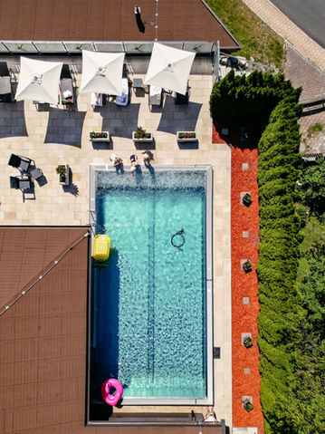 Draufsicht auf den Aussenpool mit Liegen und Sonnenschirmen im Hotel Alte Post. Klares Wasser und Entspannungsbereich.