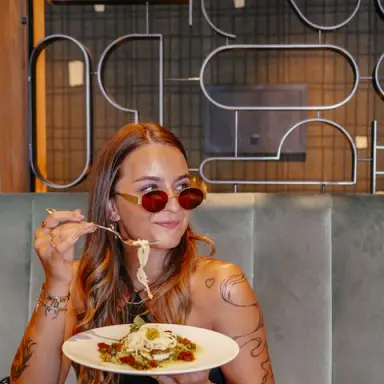 Junge Frau mit Sonnenbrille genießt Pasta im stilvollen Restaurant des Hotel Alte Post.