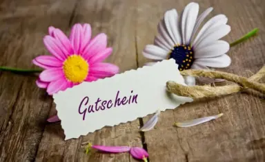 Gutschein für das Konsum Berghotel Oberhof mit rosa und weißen Blumen auf rustikalem Holzuntergrund.