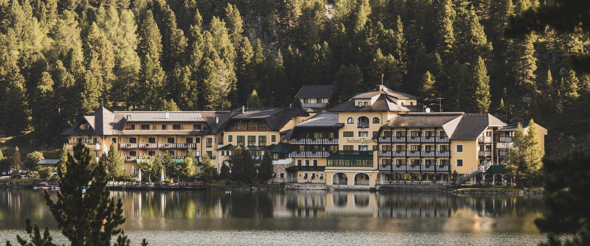 Romantik Seehotel Jägerwirt in Turracher Höhe – Hotelansicht am Seeufer im Sommer | Wellnesshotel Kärnten