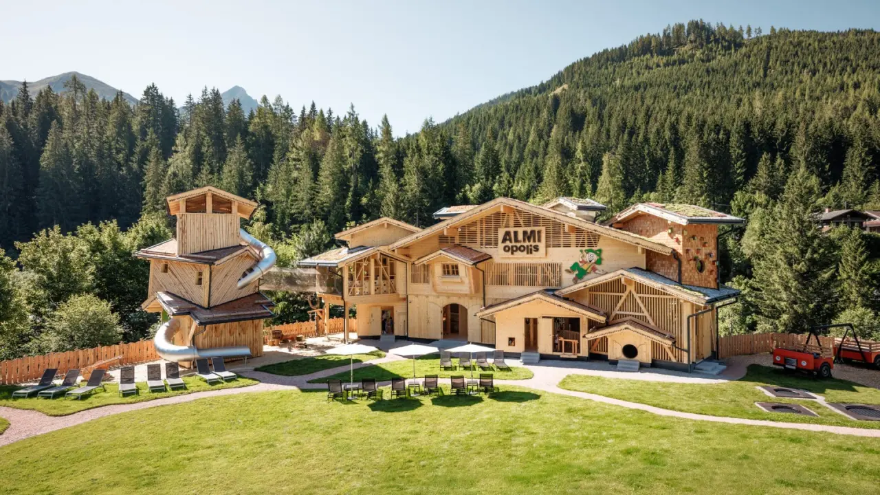 Aussenansicht des Almhof Family Resort & SPA mit dem Almi Opolis Kinderbereich und Bergpanorama.