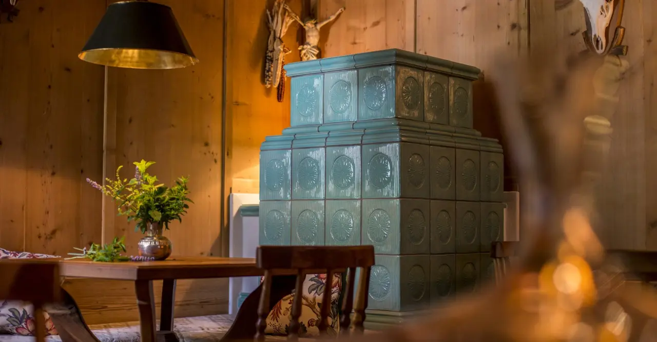 Traditioneller Kachelofen und Holzwände im Genießer-Hotel Theresa. Gemütliche Atmosphäre mit frischen Kräutern.