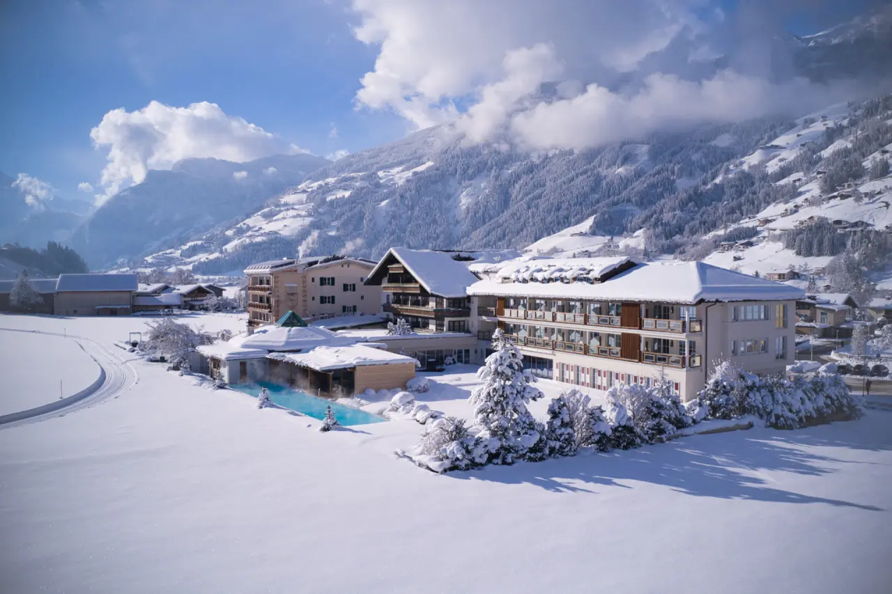 Genießer-Hotel Theresa im Winter mit beheiztem Aussenpool und verschneiter Berglandschaft.