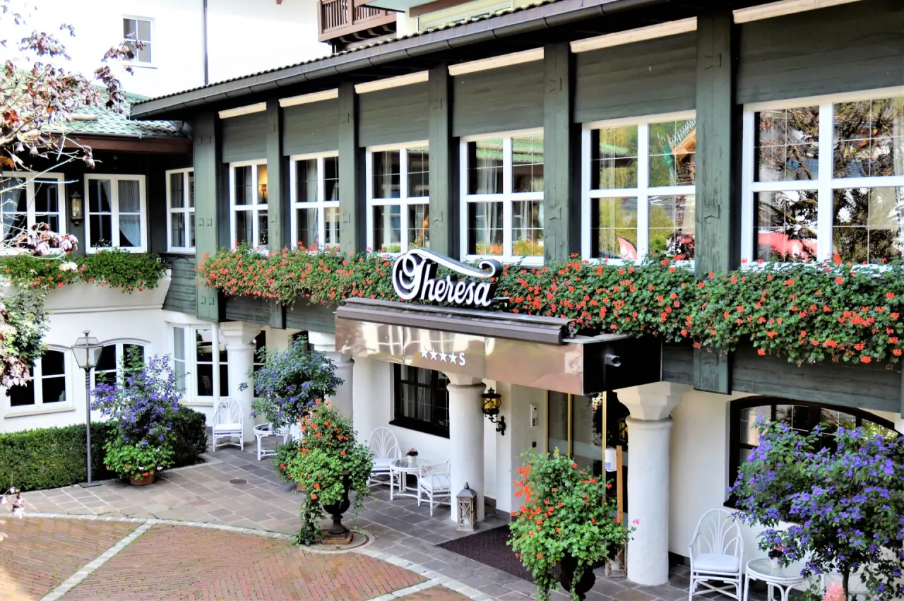 Blumengeschmückter Eingangsbereich des Genießer-Hotel Theresa mit traditioneller Architektur und gemütlichen Sitzgelegenheiten.