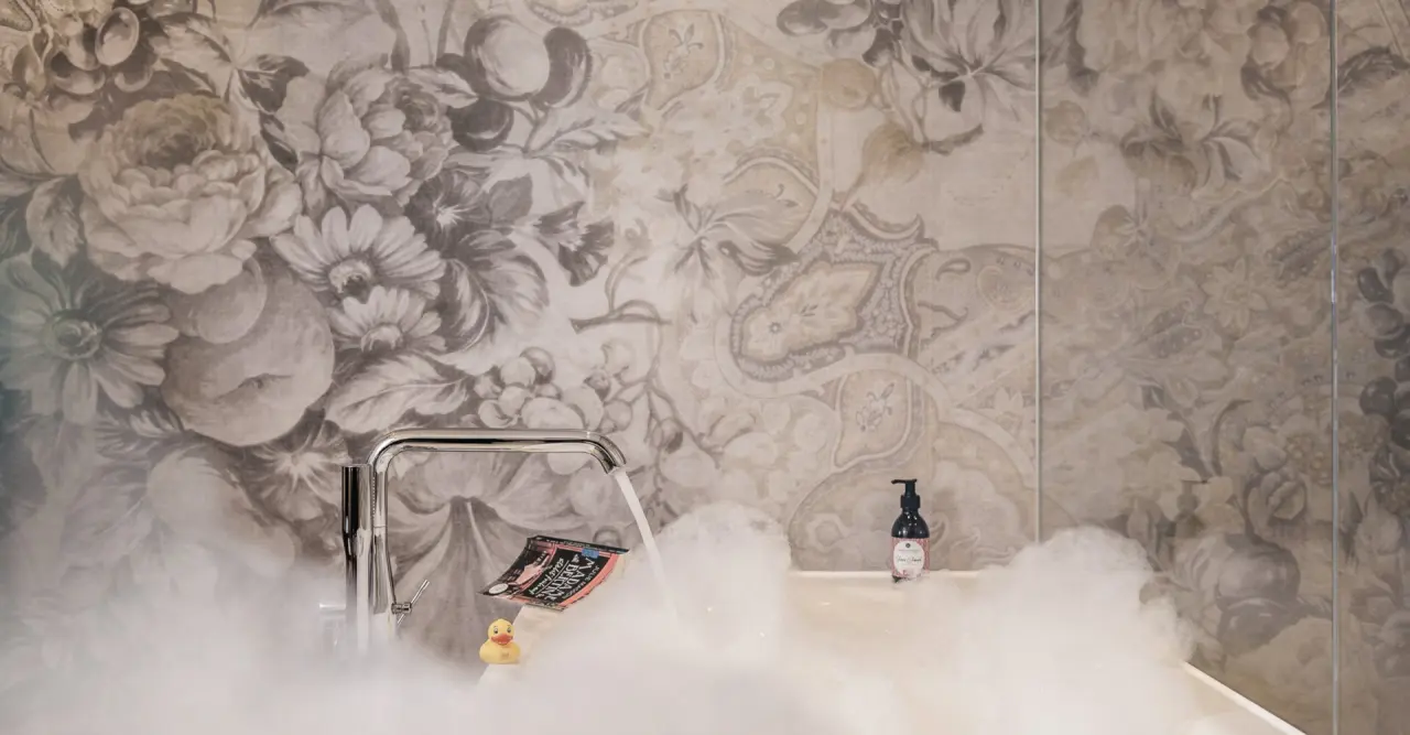 Entspannendes Schaumbad mit fließendem Wasser und floraler Tapete im Badezimmer des Genießer-Hotel Theresa.