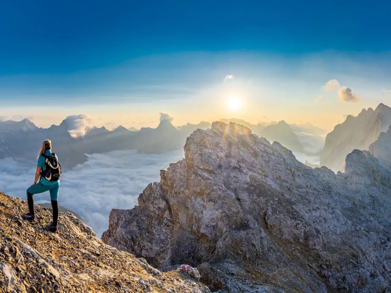 Wanderin blickt auf Nebelmeer und Sonnenaufgang in den Alpen bei Schloss Elmau.