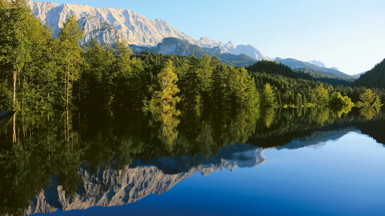 Majestätischer Bergsee mit Wald und Alpenpanorama, Spiegelung im klaren Wasser bei Schloss Elmau.