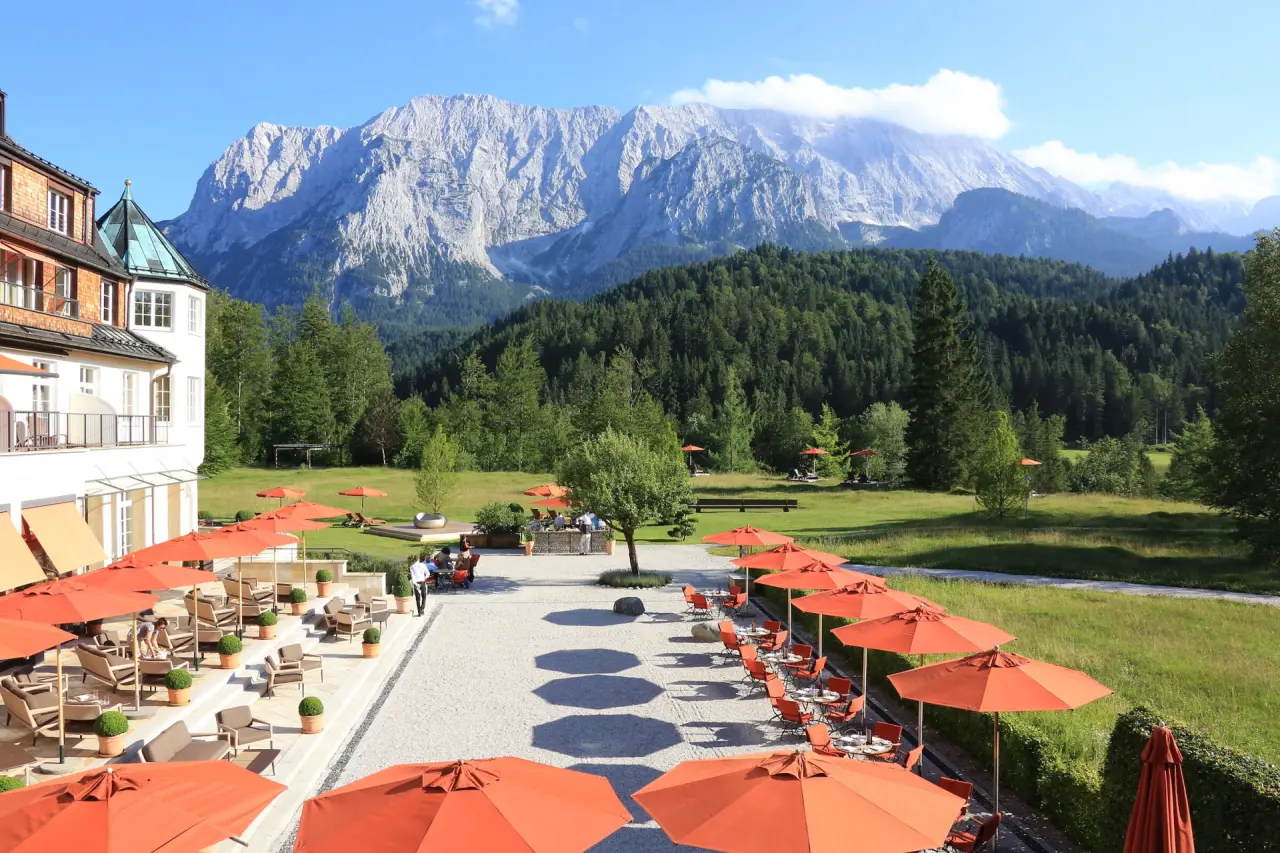 Schloss Elmau Hotel mit großer Sonnenterrasse, Garten und majestätischem Alpenpanorama im Wettersteingebirge, Bayern.