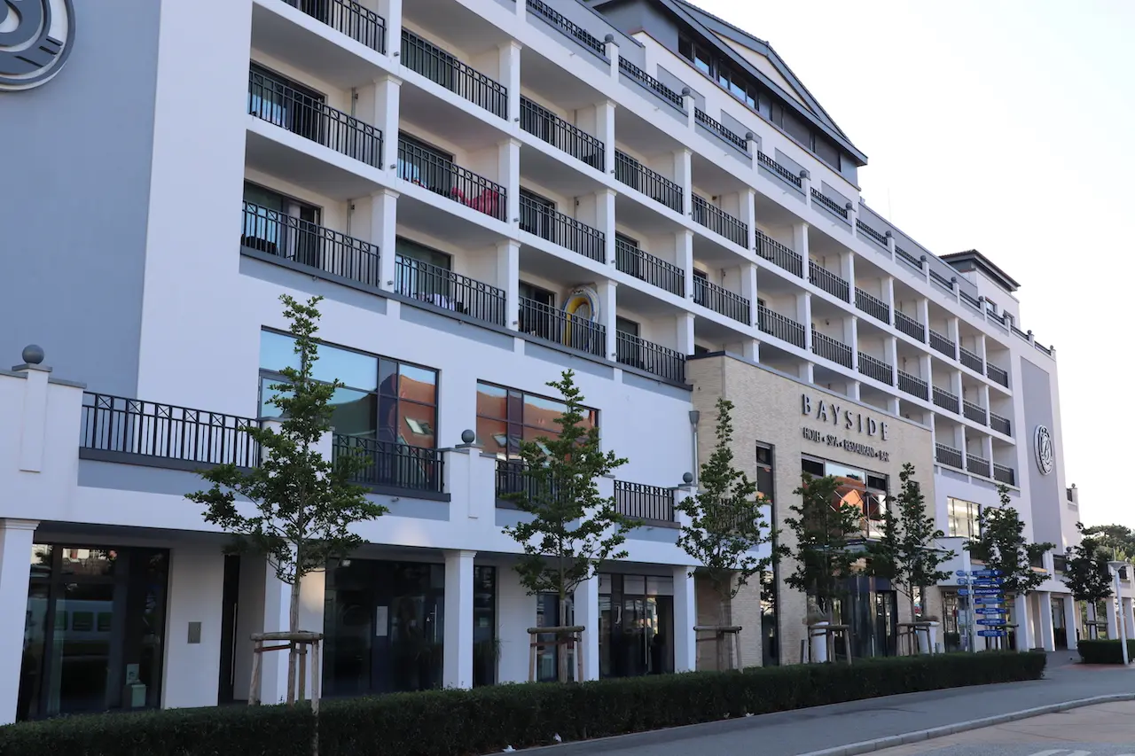 Modernes Bayside Hotel mit vielen Balkonen und dem Schriftzug 'Hotel + Spa + Restaurant + Bar' an der Fassade.