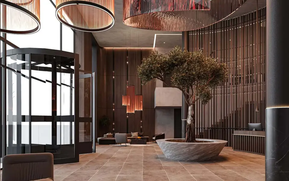 Moderne und stilvolle Lobby des Bayside Hotels mit hoher Decke, Design-Beleuchtung und einem Olivenbaum.