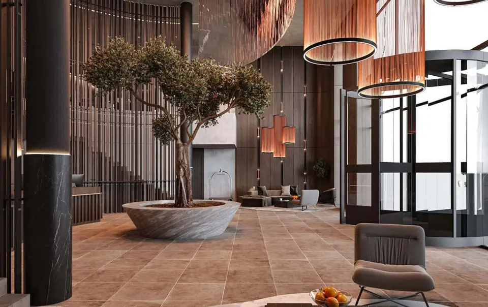 Moderne und luxuriöse Lobby des Bayside Hotels mit Olivenbaum, stilvollen Leuchten und bequemen Sitzbereichen.