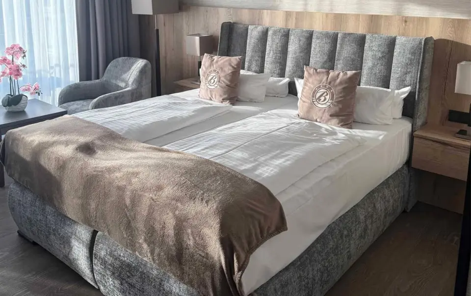 Gemütliches Doppelzimmer im Bayside Hotel mit modernem Bett, Nachttischen und Sitzgelegenheit am Fenster.