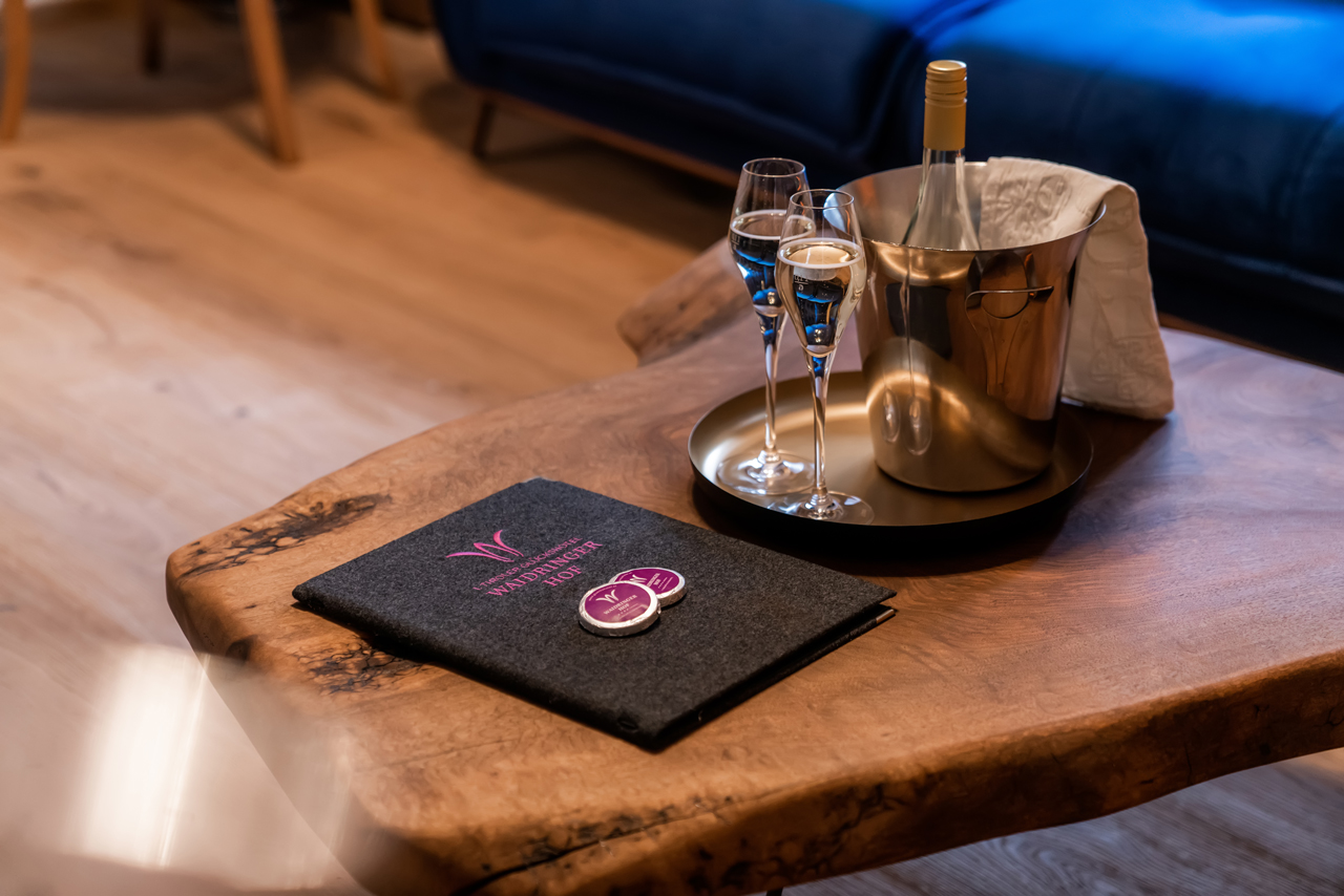 Waidringer Hof in Waidring – Willkommensgetränk und Hotelbroschüre auf einem Holztisch | Wellnesshotel Tirol