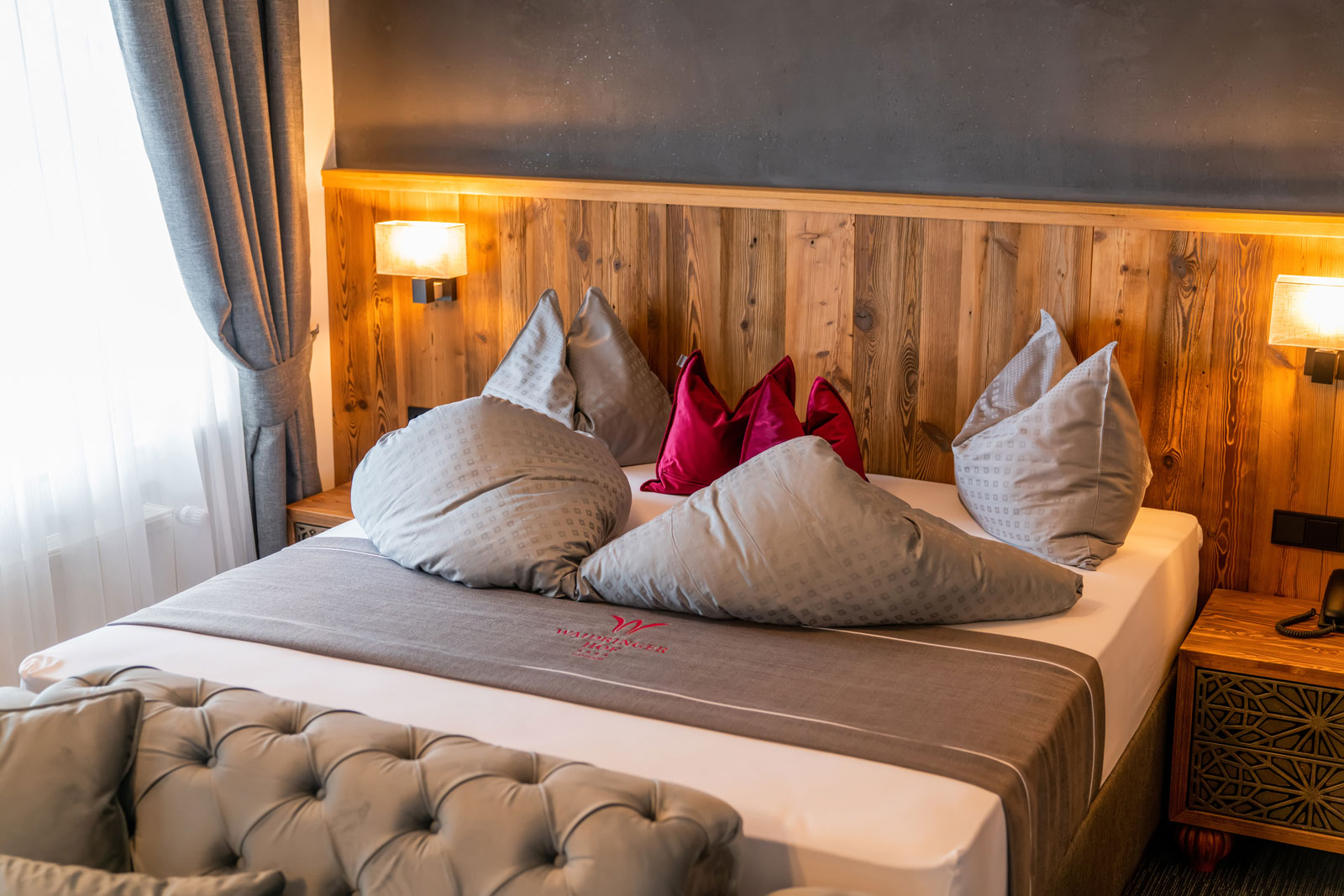 Waidringer Hof in Waidring – Komfortables Doppelbett mit Holzkopfteil im Hotelzimmer | Wellnesshotel Tirol