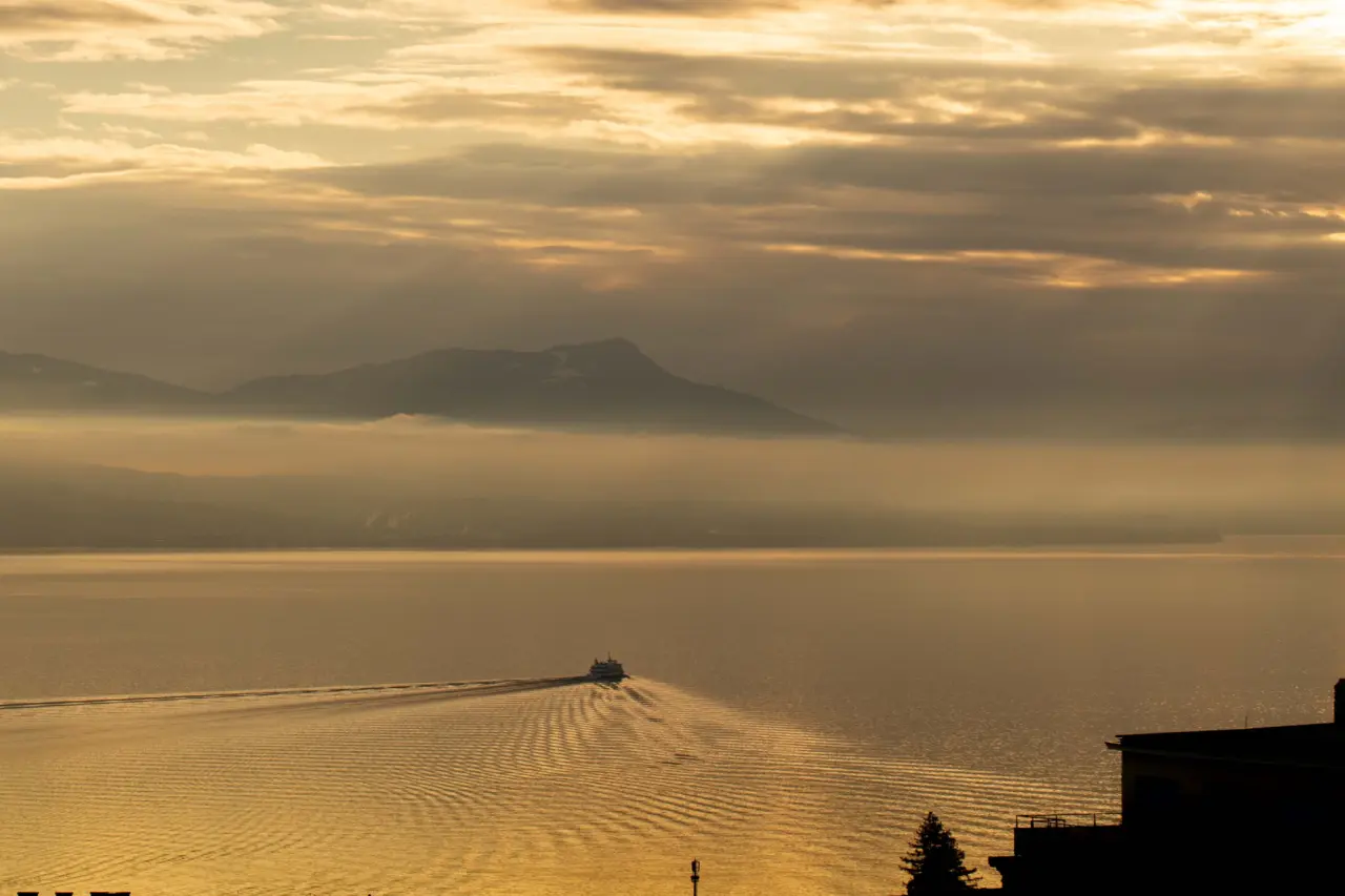 Sonnenuntergang über dem Genfersee mit Schiff und Alpenpanorama, gesehen vom Hotel Lausanne Palace.
