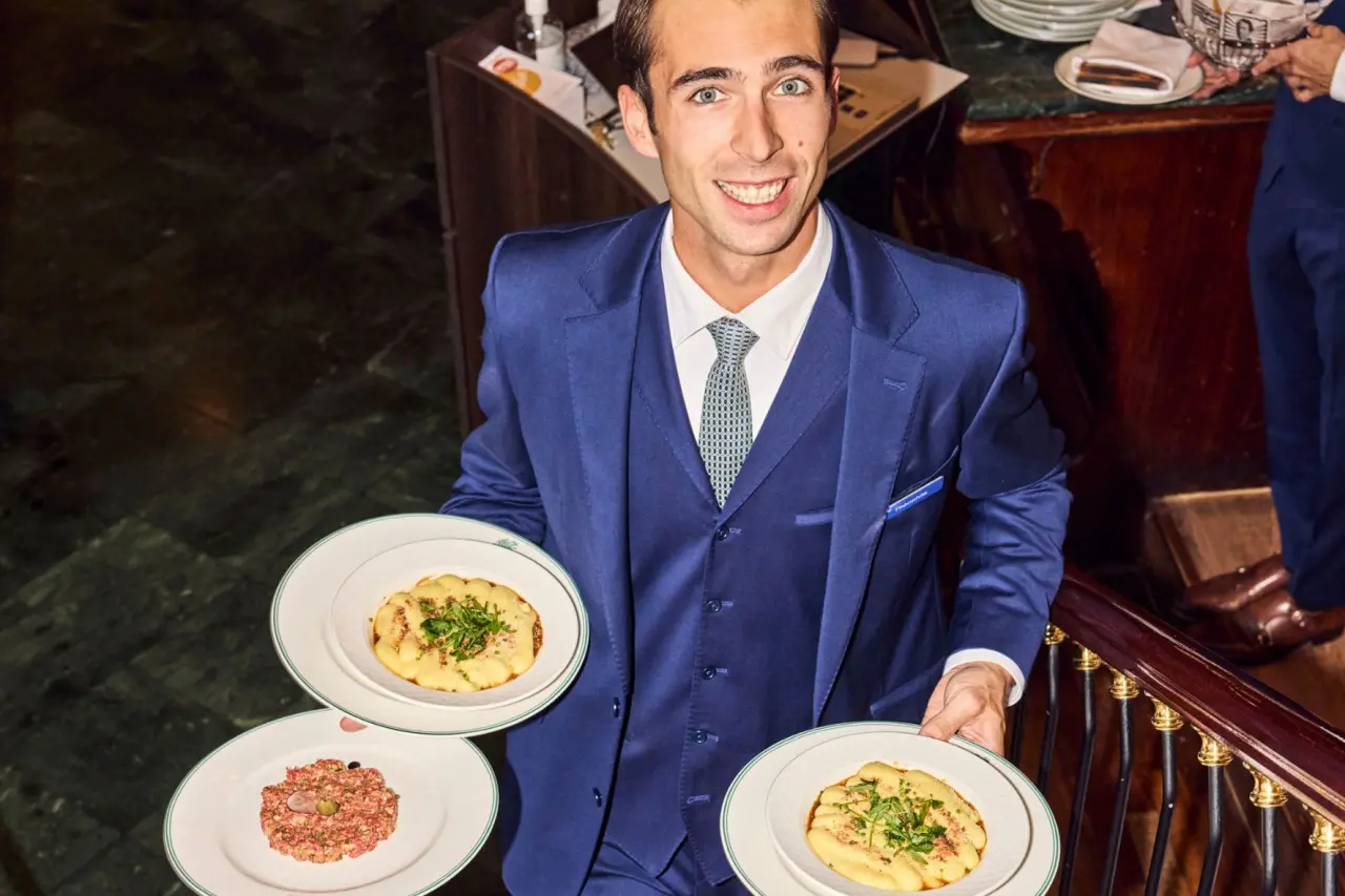 Freundlicher Kellner des Hotel Lausanne Palace serviert kunstvoll angerichtete Speisen im eleganten Restaurant.