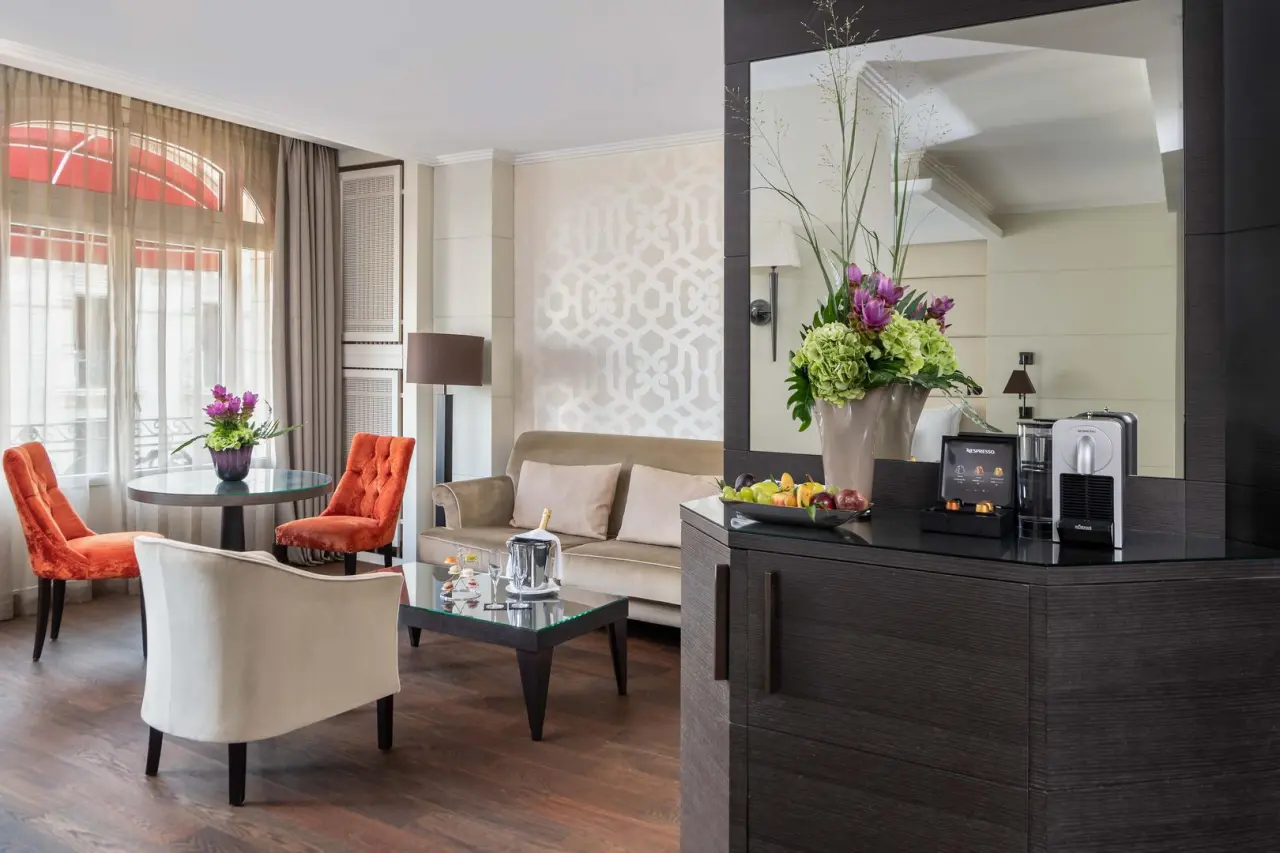 Elegante Suite im Hotel Lausanne Palace mit gemütlichem Sitzbereich, Nespresso-Maschine und frischen Blumen.