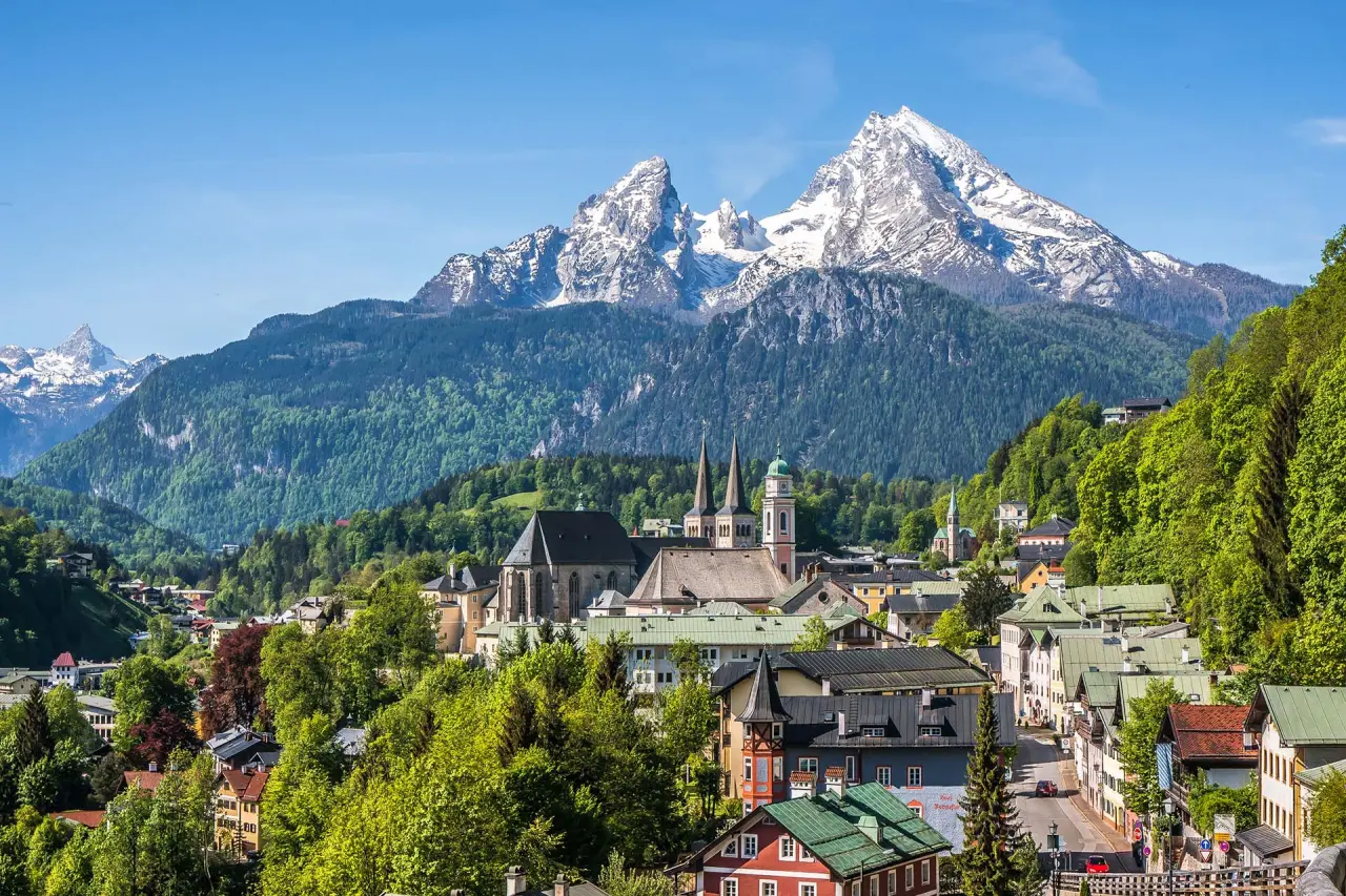 Malerischer Panoramablick auf Berchtesgaden mit Watzmann und Stiftskirche, umgeben von grünen Wäldern. Naturhotel Reissenlehen.