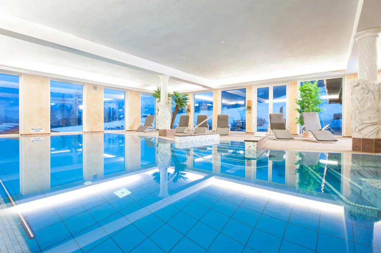 Grosszügiger Innenpool mit Liegebereich und Winterlandschaft im Naturhotel Reissenlehen