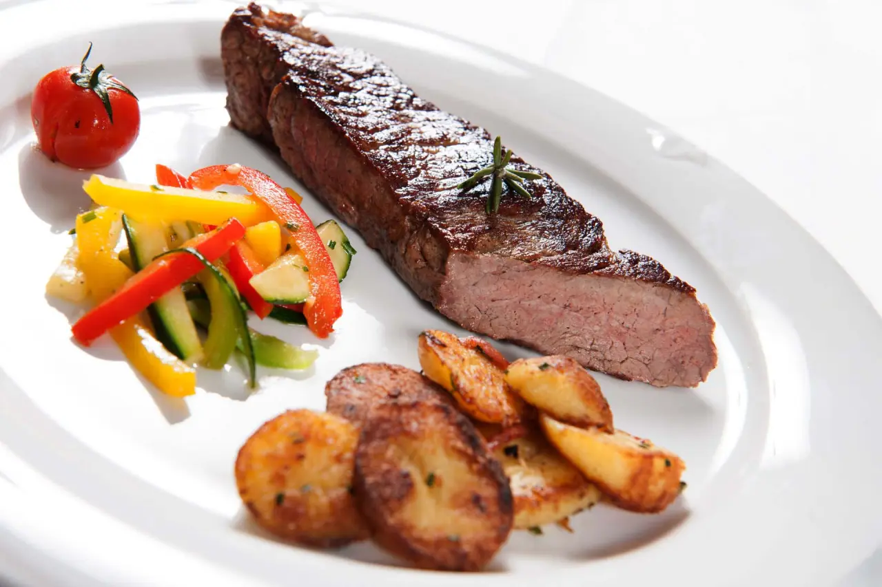 Ansprechend angerichtetes Steak mit Rosmarin, Bratkartoffeln und Gemüse im Restaurant des Naturhotel Reissenlehen.