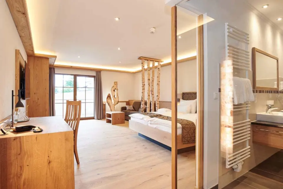Helles, modernes Hotelzimmer im Naturhotel Reissenlehen mit viel Holz, Doppelbett, Schreibtisch und Badzugang.