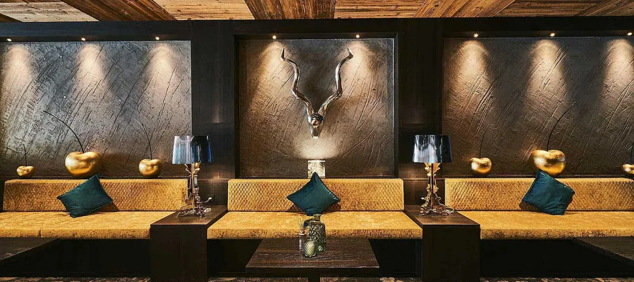Luxuriöse Lounge im Wellness Hotel Zum Bräu mit bequemen Sitzgelegenheiten, stilvoller Beleuchtung und Hirschgeweih-Dekoration.