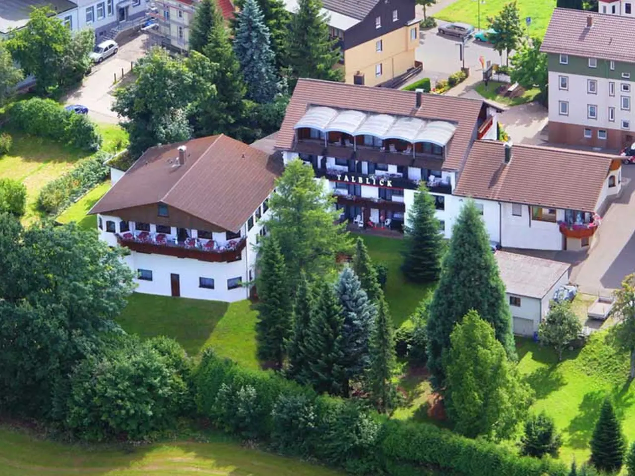 Luftaufnahme des Wellness-Hotel Cafe Talblick mit seinen Gebäuden, umgeben von Bäumen und grünen Wiesen.