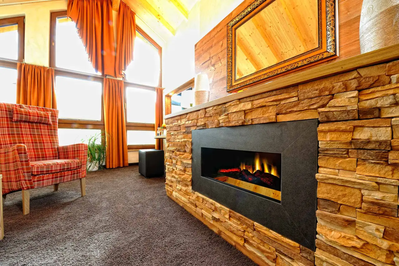 Gemütlicher Sitzbereich mit Kamin und Sessel im Wellness-Hotel Cafe Talblick