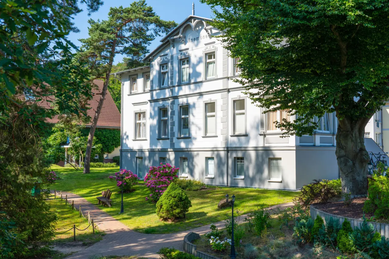 Historische Villa Anemone des Ostseehotel - Villen im Park mit gepflegtem Garten und blühenden Rhododendren.