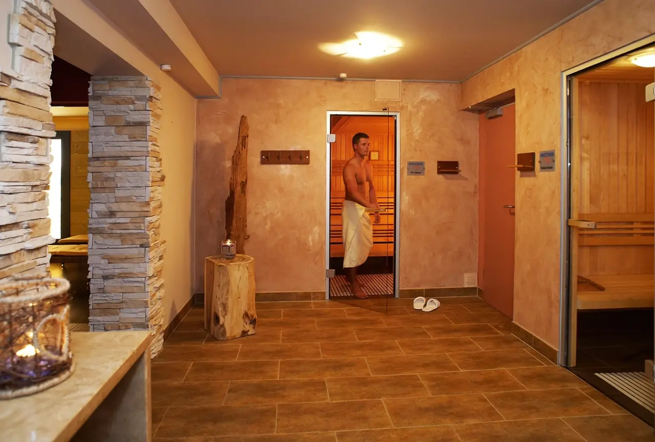 Saunabereich mit finnischer Sauna und einem Gast in Handtuch im Ostseehotel - Villen im Park.