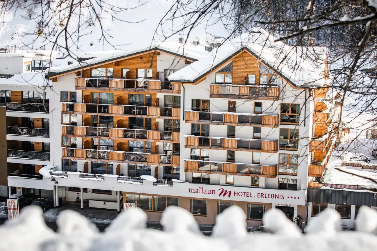 Winterliche Aussenansicht des Hotel Mallaun mit verschneiten Balkonen und Dächern in den österreichischen Alpen.
