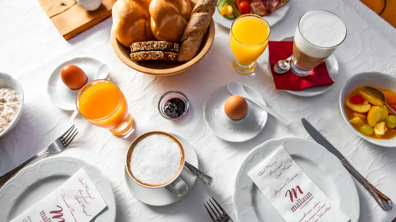 Reichhaltiges Frühstücksbuffet mit frischen Brötchen, Säften und Kaffee im Hotel Mallaun.