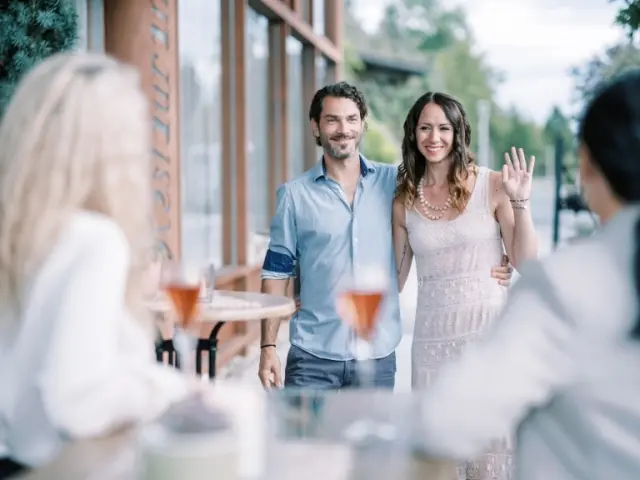 Lächelndes Paar auf der Restaurantterrasse des Garten-Hotel Ochensberger, Gäste genießen Roséwein im Freien.