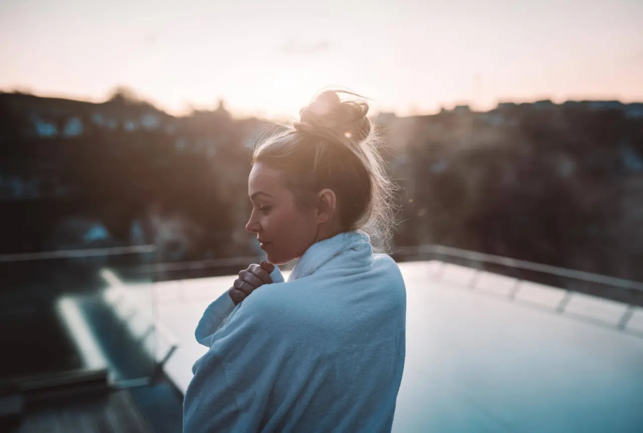 Frau im Bademantel genießt den Sonnenuntergang auf einer Terrasse im DIEDRICH Wellnesshotel & SPA.