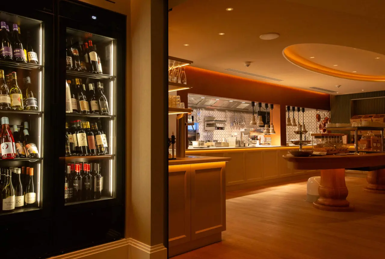 Modernes Restaurant mit offener Küche und beleuchtetem Weinkühlschrank im DIEDRICH Wellnesshotel & SPA.