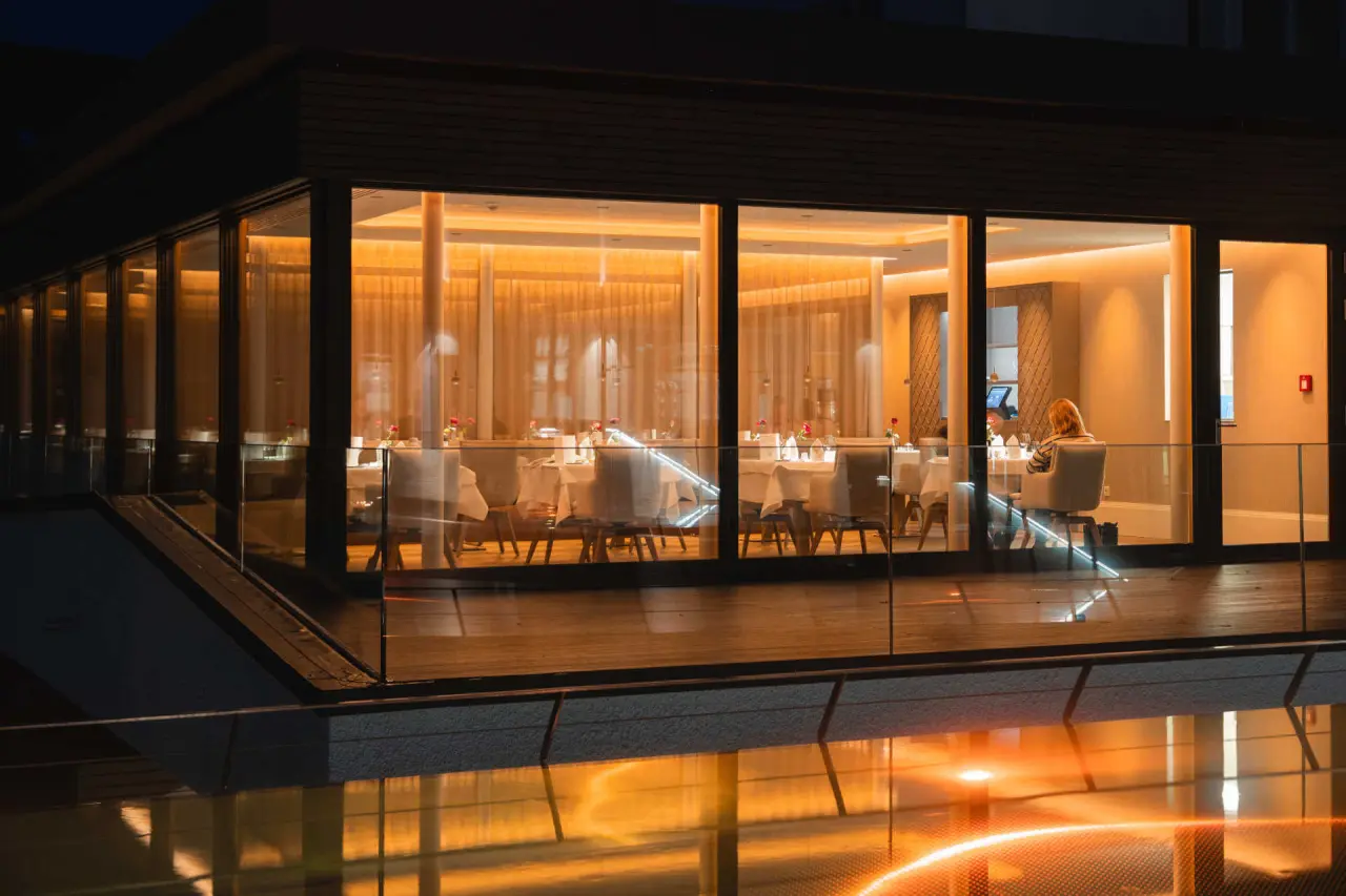 Elegantes Restaurant mit warmem Licht und Spiegelung im Wasser am Abend im DIEDRICH Wellnesshotel & SPA.