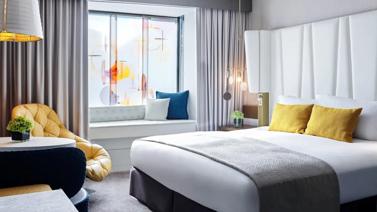Modernes Hotelzimmer im Sofitel Munich Bayerpost mit großem Bett, Sitzbereich am Fenster und stilvoller Einrichtung.