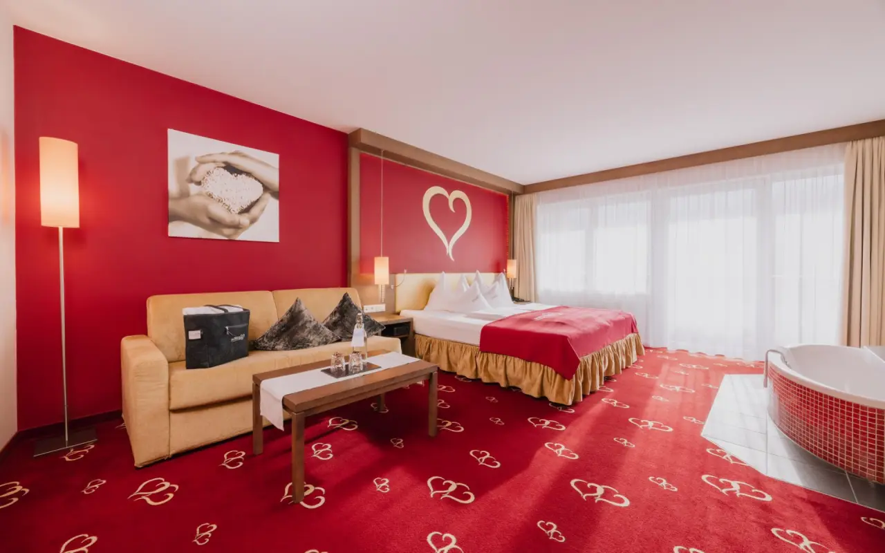 Romantisches Hotelzimmer mit Doppelbett, Sofa und freistehender Badewanne im Romantik & Spa Alpen-Herz.