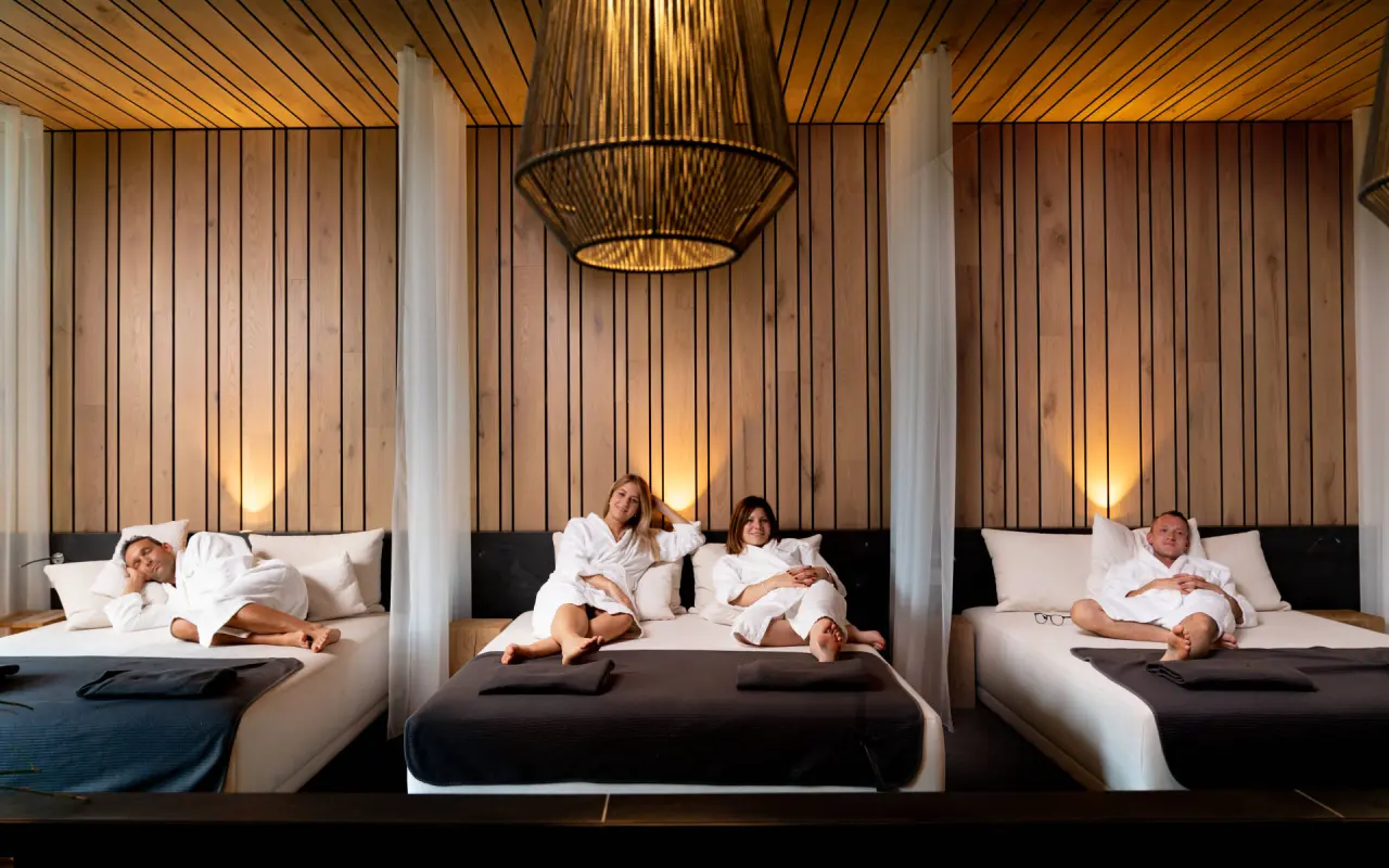 Gäste entspannen in Bademänteln auf bequemen Liegen im modernen Ruheraum des Michels Wohlfühlhotel Spa-Bereichs.