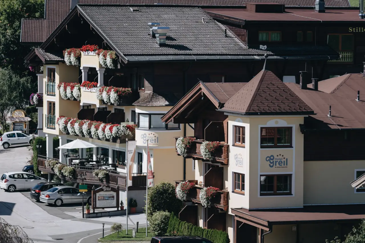 Traditionelle Aussenansicht des Hotel Der Greil mit blumengeschmückten Balkonen und alpiner Architektur.
