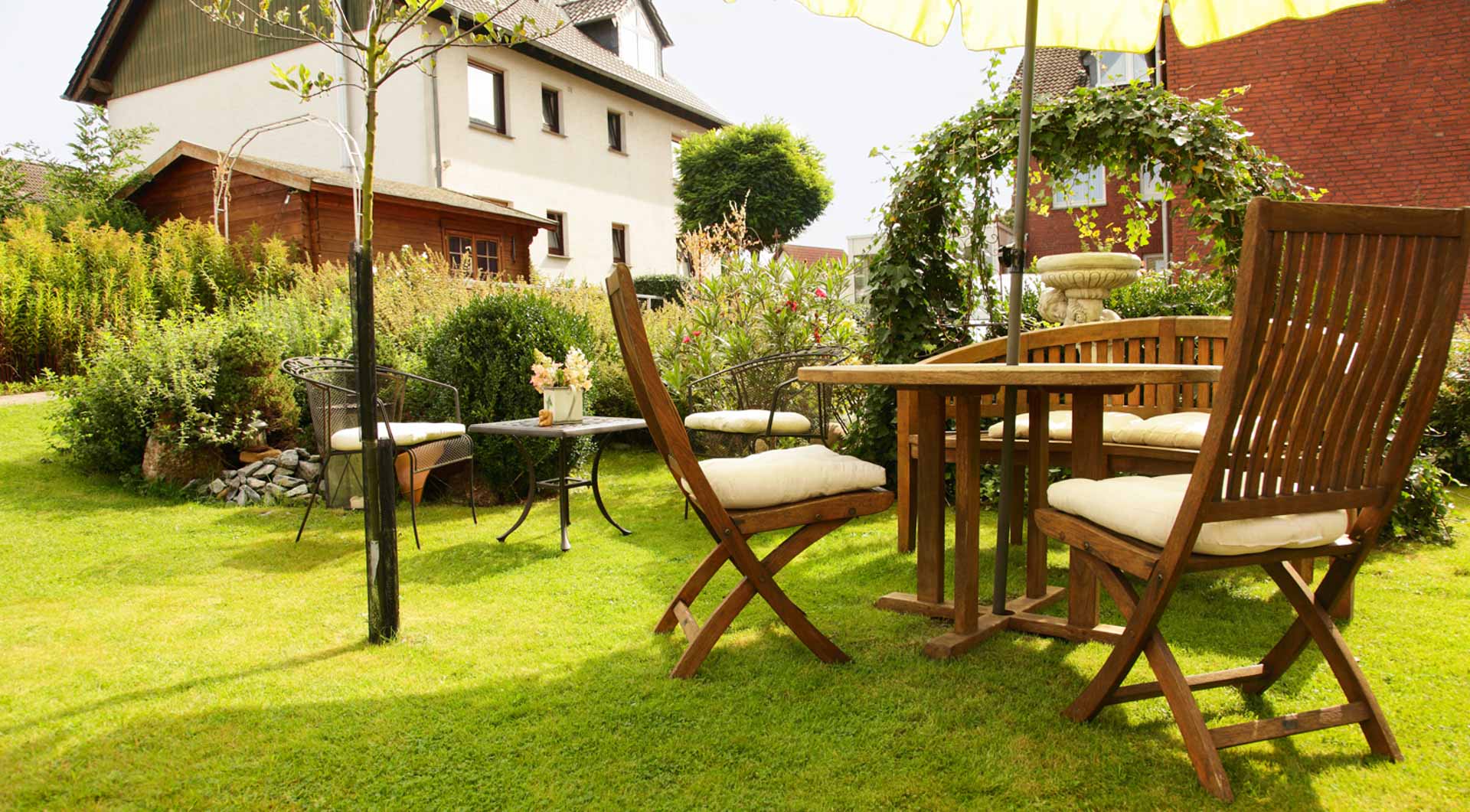 Hotel Wulff in Bad Sassendorf – Gemütlicher Gartenbereich mit Holztischen und Stühlen | Wellnesshotel Sauerland