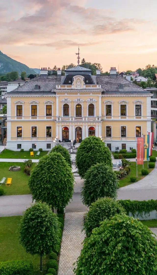 Historische Villa Seilern Vital Resort Fassade im Abendlicht mit gepflegtem Garten und Alpenpanorama.