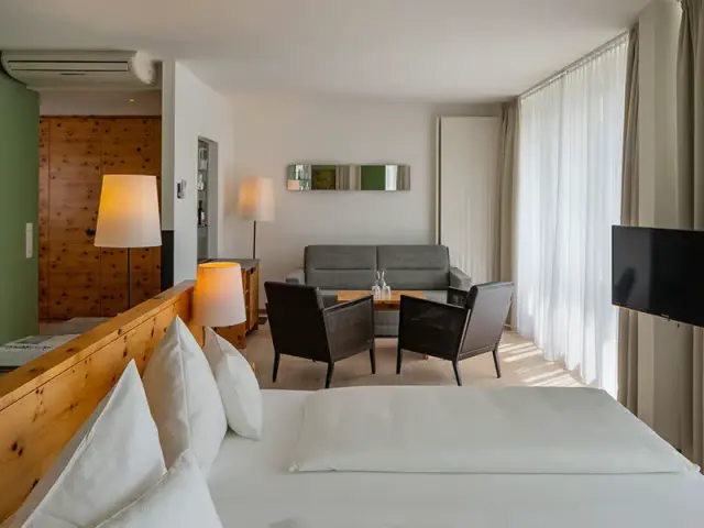 Geräumiges Hotelzimmer mit Doppelbett, Sitzbereich und Holzelementen im Villa Seilern Vital Resort.