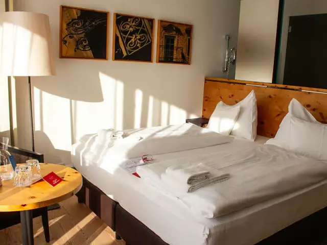 Helles Doppelzimmer im Villa Seilern Vital Resort mit Holzkopfteil, weisser Bettwäsche und sonnigem Ambiente.