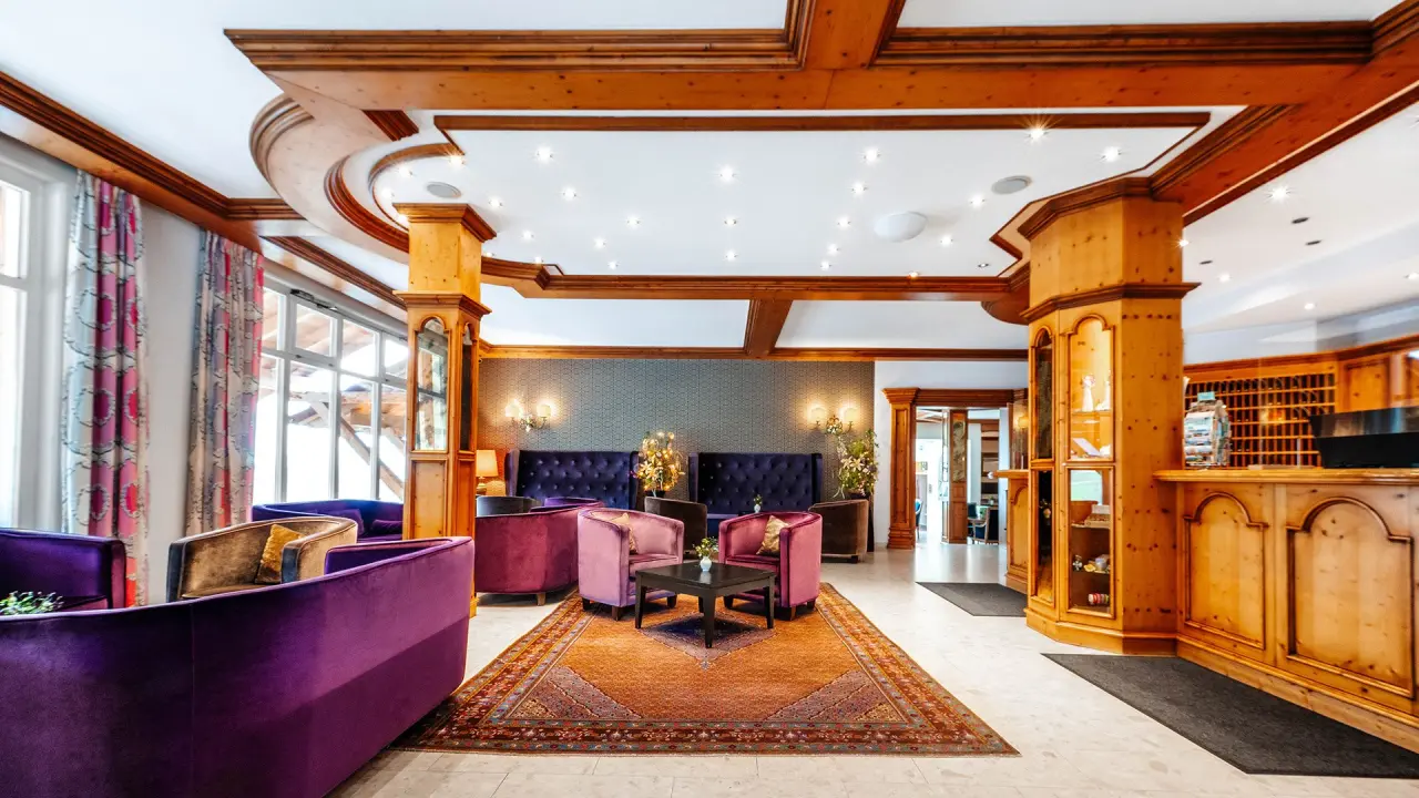 Einladende Hotellobby mit Rezeption, gemütlichen Sitzbereichen und Holzvertäfelung im Burghotel Am Hohen Bogen.