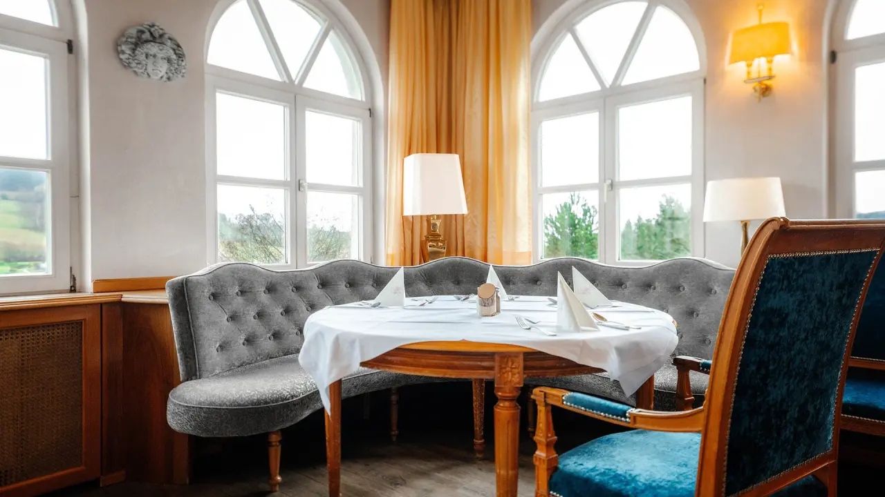 Gemütlicher Restaurantbereich mit Rundbank und Blick ins Grüne im Burghotel Am Hohen Bogen.