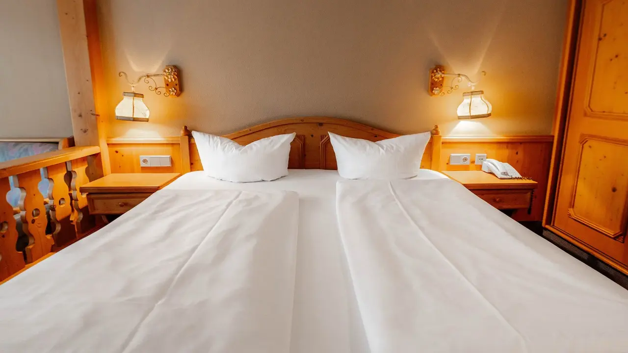 Gemütliches Doppelzimmer im traditionellen Stil mit Holzelementen und warmem Licht im Burghotel Am Hohen Bogen.
