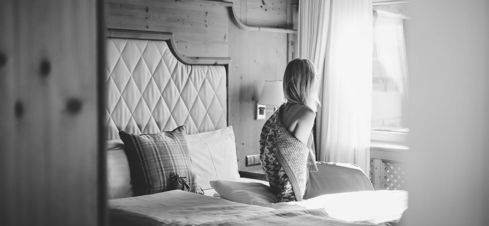 Burg Hotel in Lech am Arlberg – Frau entspannt im gemütlichen Hotelzimmer mit Bergblick | Wellnesshotel Arlberg